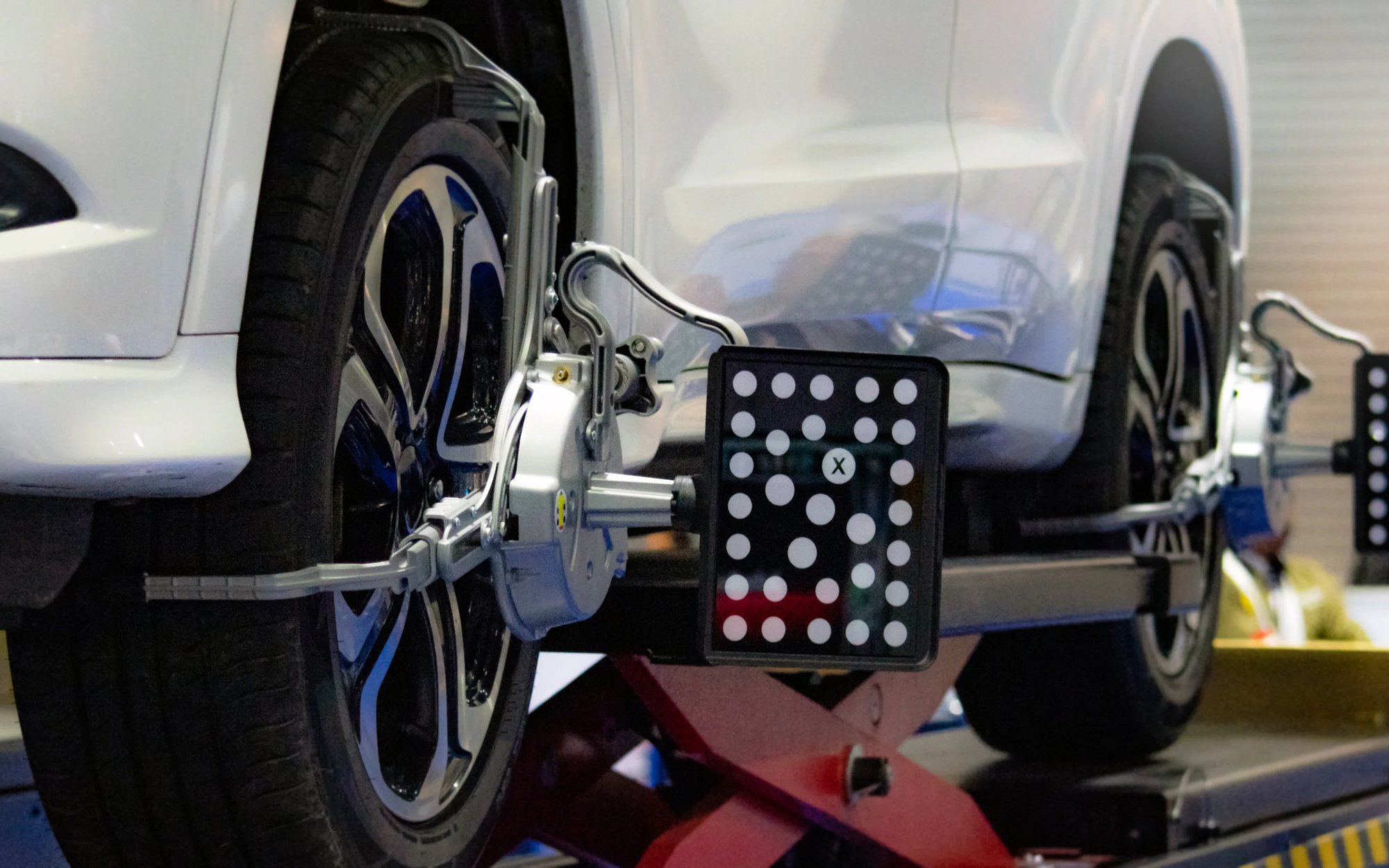 A vehicle wheel is precisely aligned and inspected in a workshop using specialized equipment for wheel alignment.