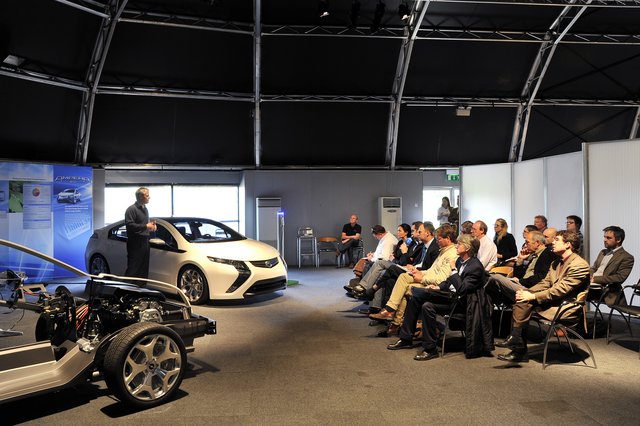 Vehicle and chassis presentation in front of a professional audience in a modern testing environment.