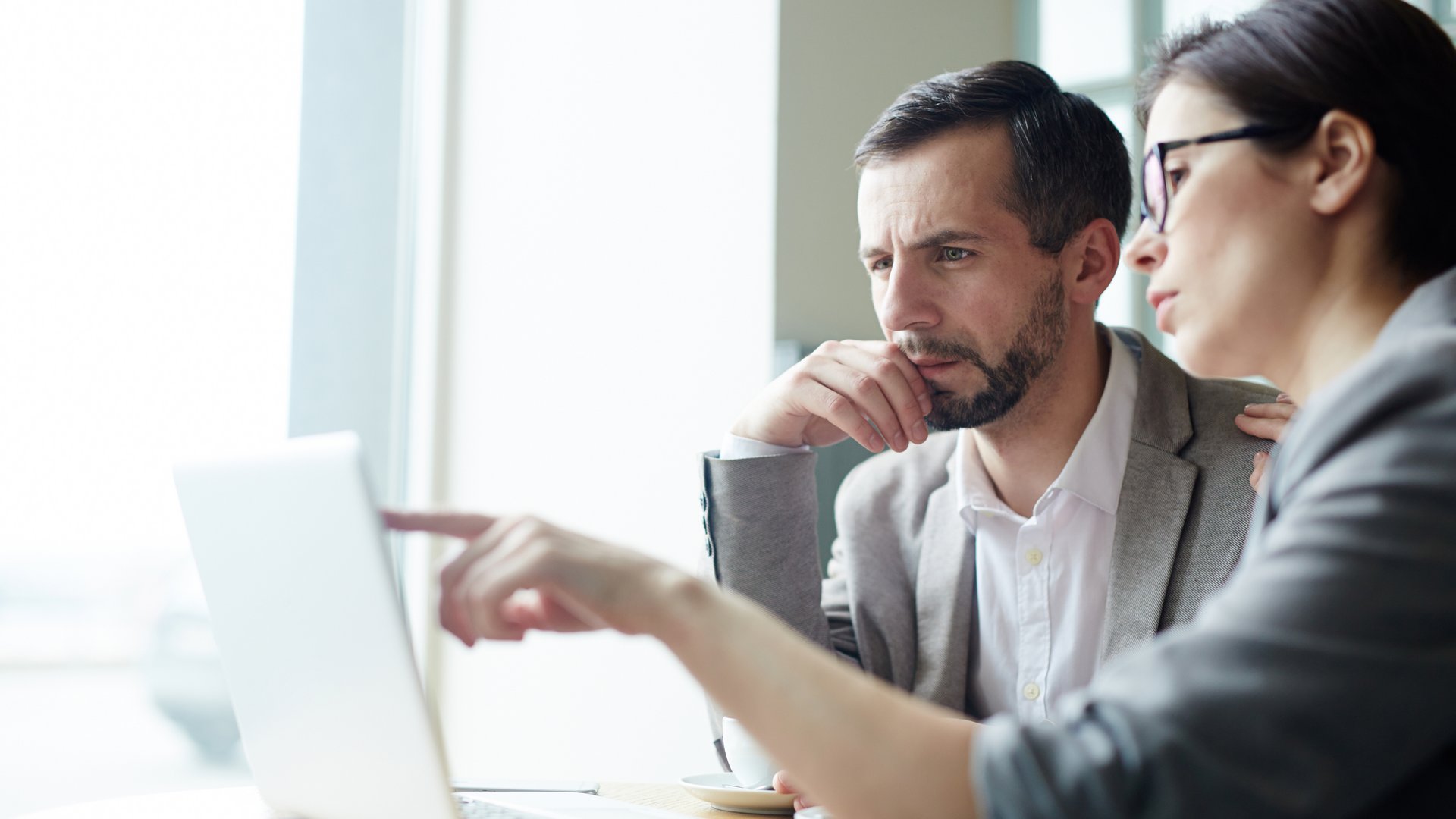 Two business professionals focused on a laptop – collaboration and consultation in an office setting.