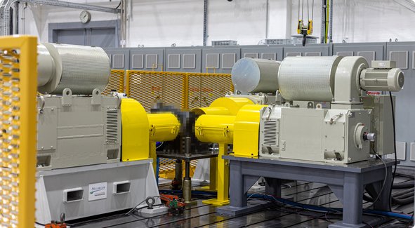 Deux grandes machines industrielles grises avec des protections jaunes se trouvent dans un hall d'usine.