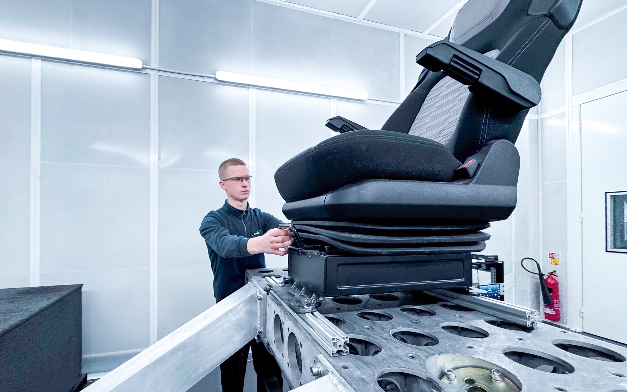 Technician testing a car seat on a test rig in a modern lab – quality assurance and ergonomic testing.