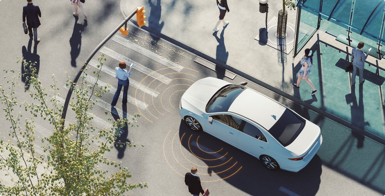 Autonomous white car detects pedestrians at a crosswalk in an urban environment.
