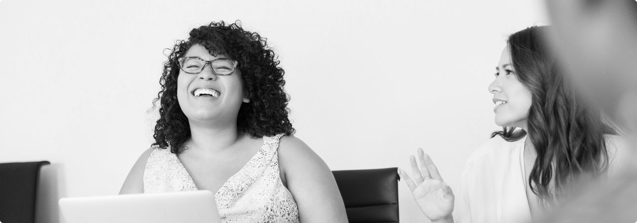 Two women laughing during a meeting – a friendly and positive work atmosphere.