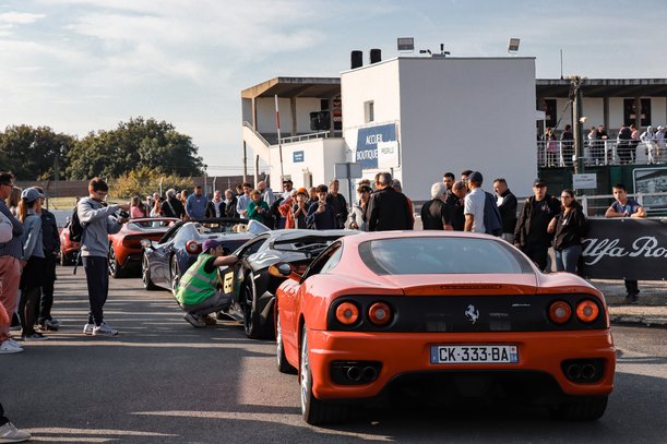Sports cars and visitors at a car event in front of a modern building – exclusive vehicle presentation or track day.