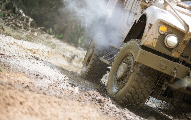 Off-road vehicle driving through muddy terrain – close-up of tires in action during test.