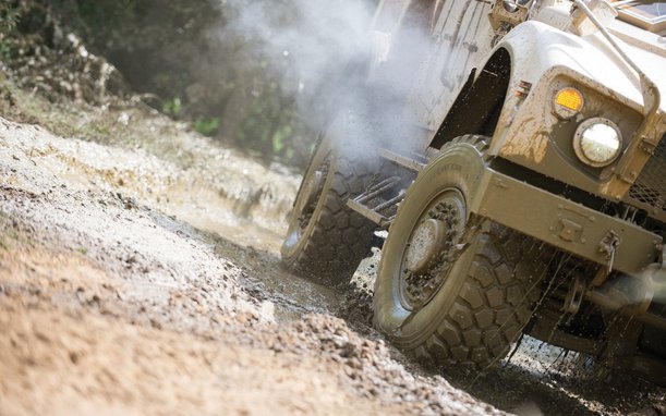 Off-road vehicle driving through muddy terrain – close-up of tires in action during test.
