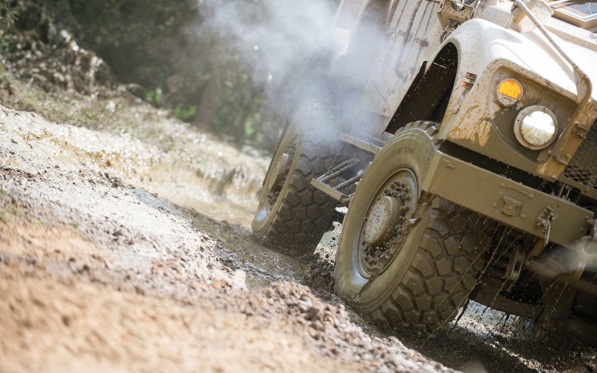 Off-road vehicle driving through muddy terrain – close-up of tires in action during test.
